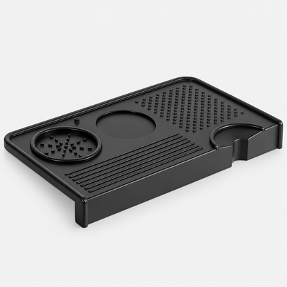 Black silicone coffee tamping mat with a counter edge lip, tool recesses and portafilter cutout.